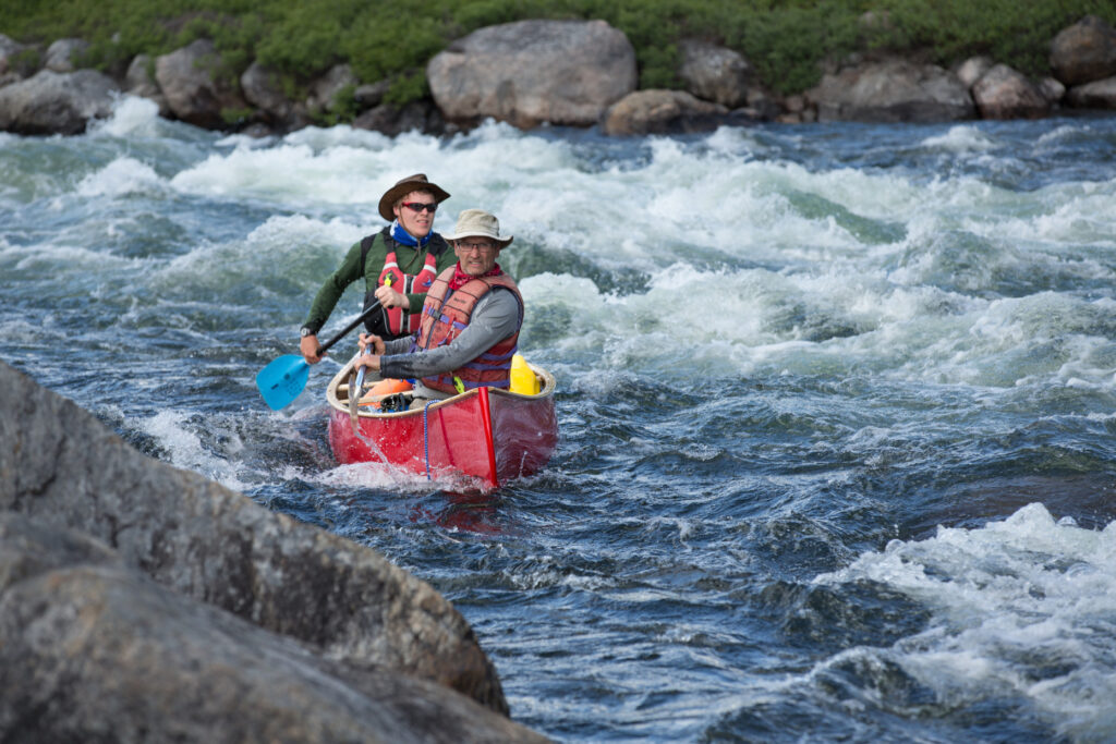 Yellowknife, NWT - Jack Stefanyk pulls a fast bow cross draw as Rylie Braun cooly tillers through a rough section on the Yellowknife River.